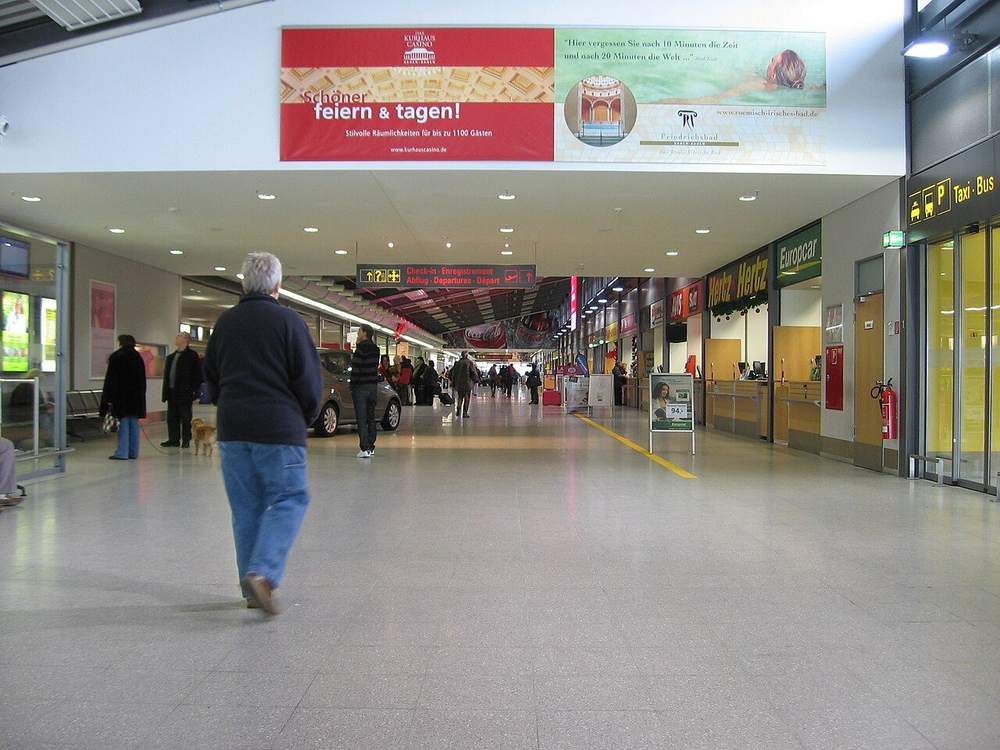 Terminalhalle des Flughafens Karlsruhe/Baden-Baden mit Reisenden auf dem Weg zum Abflugbereich